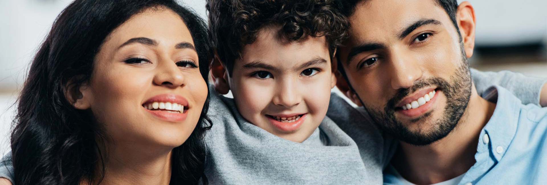A Hispanic couple with a child. smiling at the camera